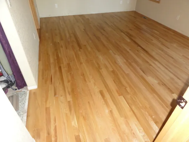Newly finished oak plank floor in an empty room, cut in cleanly along the walls