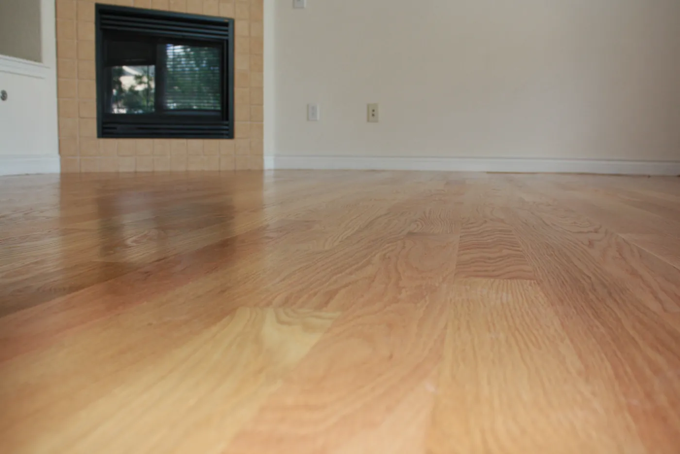 Low angle view of a smooth satin finished oak floor in a living room with a fireplace
